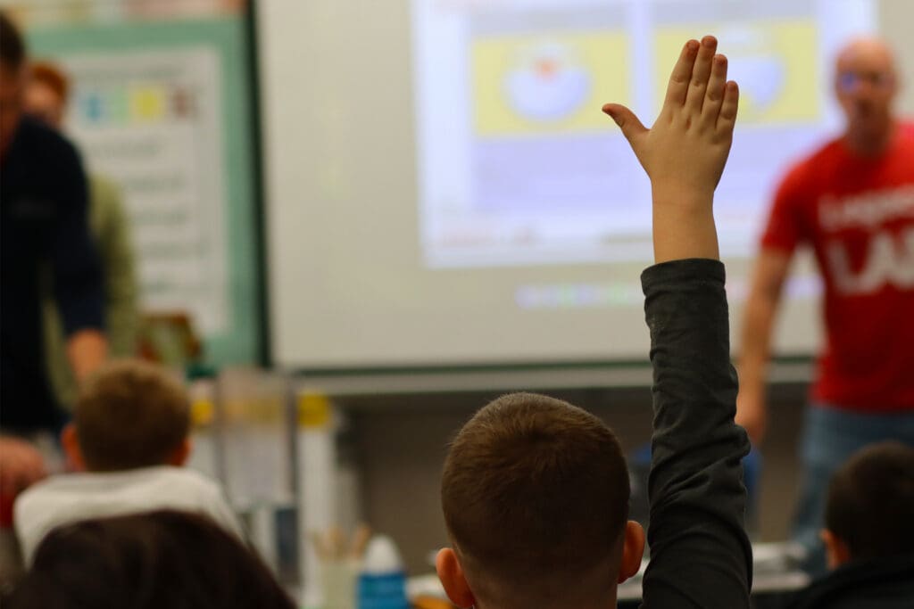 student raising their hand to answer a question during a Legacy LAB classroom activity